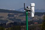 Temperatur- und Luftfeuchtesensor in einer zwangsbelüfteten Wetterhütte und im Hintergrund die Photovoltaikanlage von Semriach